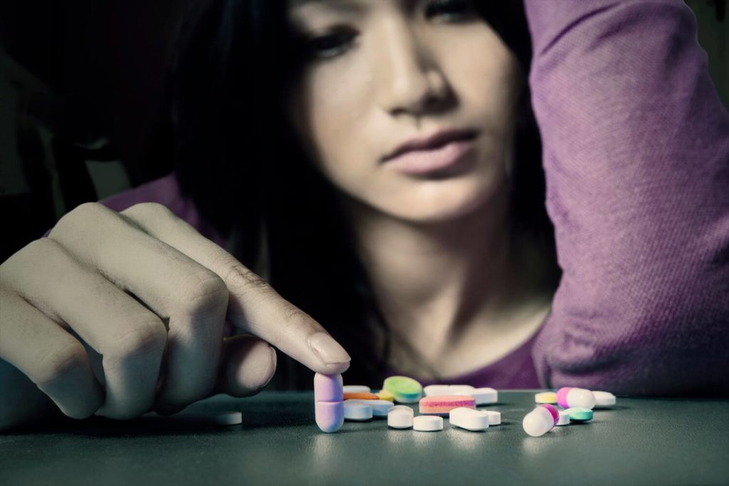 Portrait of an addiction teenage girl with narcotic shaped pills in the bedroom