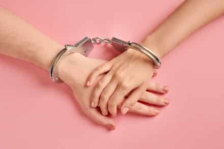 Male and female hands in handcuffs.